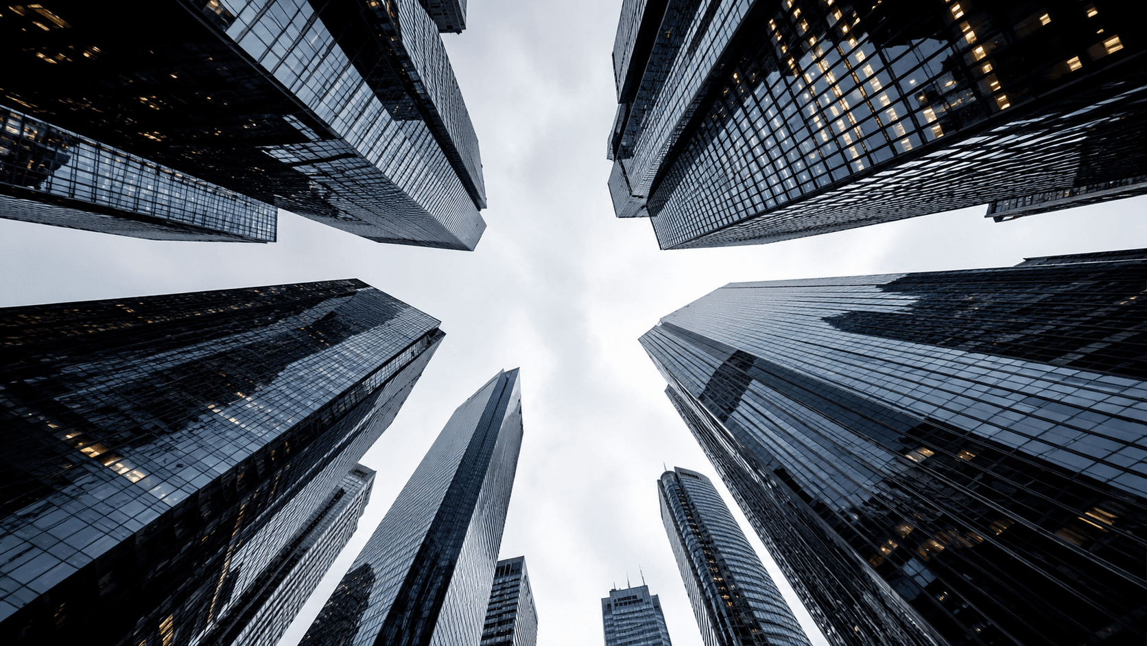 Glass towers viewed from below against a cloudy sky